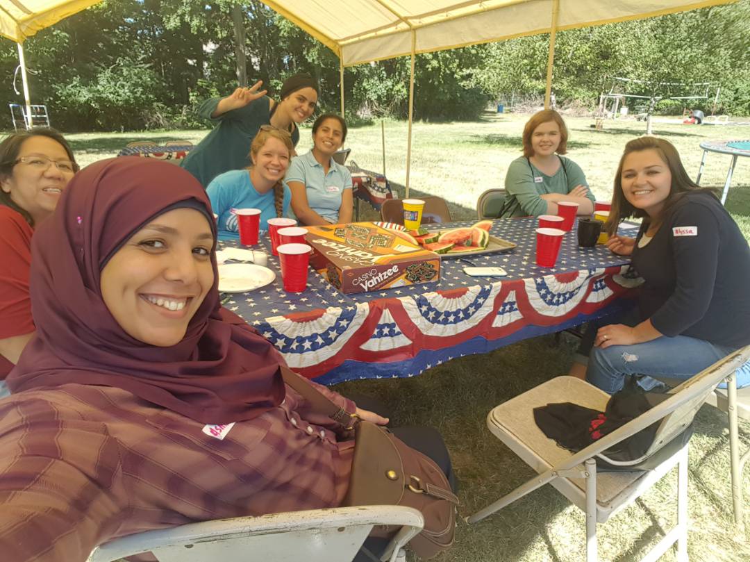 Six humphrey fellows sit at a picnic table on a sunny day.