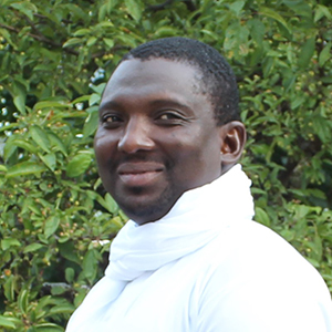 Garba Hamadou smiling in front of leafy backdrop