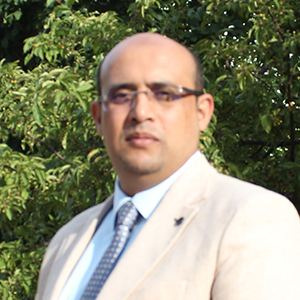 Ali Sharwan standing in front of leafy background